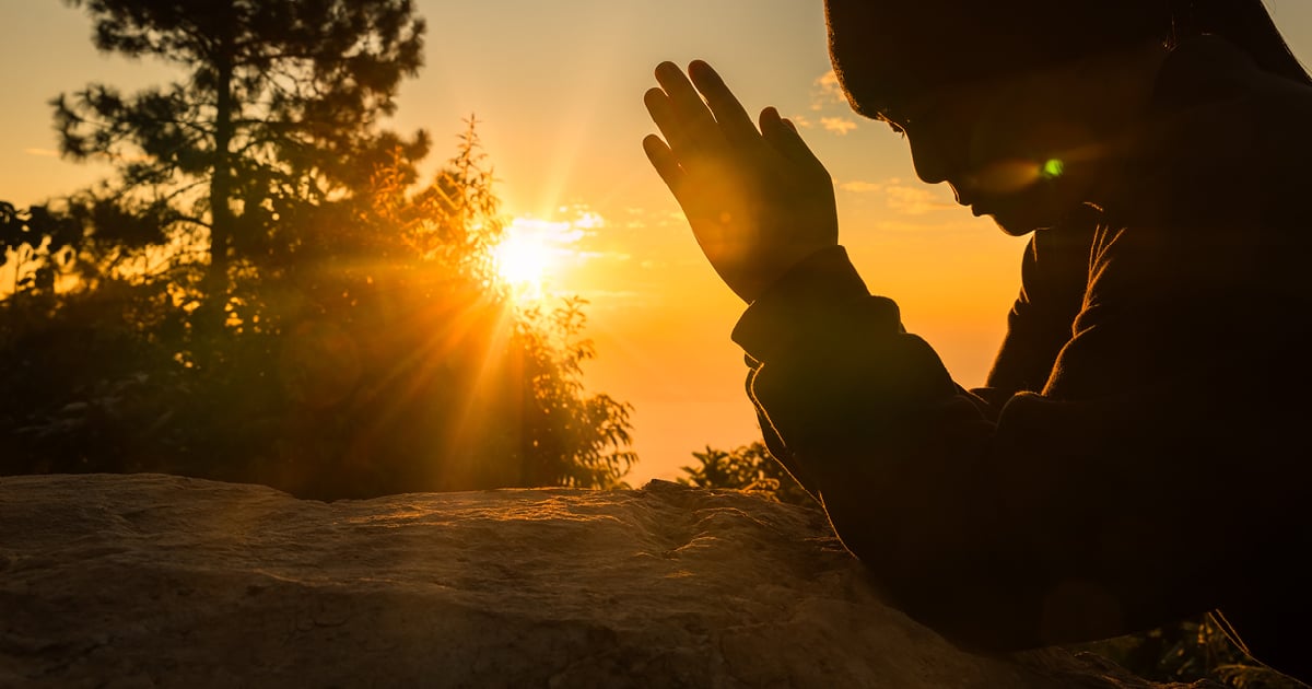 Today's daily devotional | A woman praying at sunset.